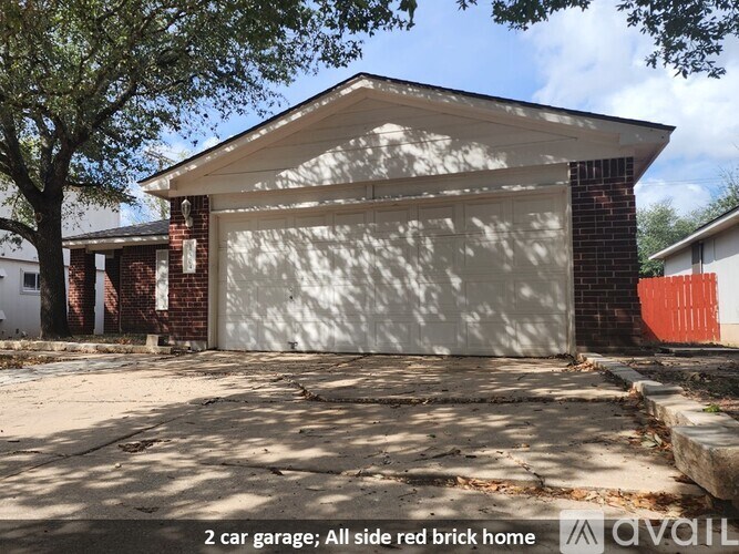 A two car garage is attached to a red brick home.