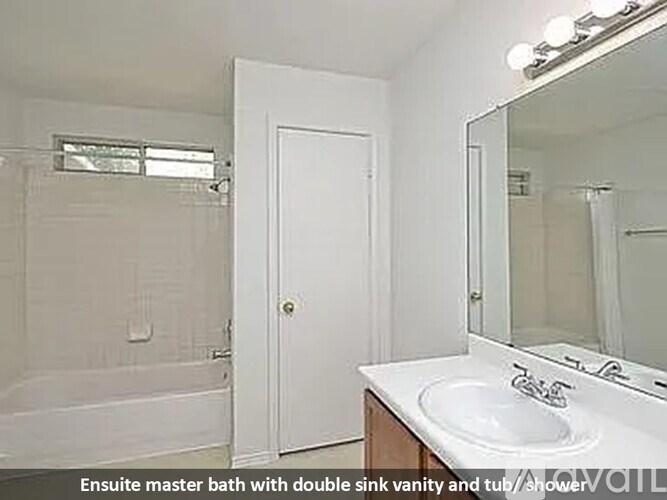A white bathroom with a double sink vanity and a tub/shower combination.
