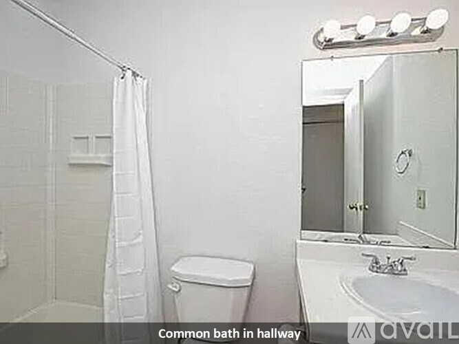 A white bathroom with a toilet, sink, and shower.