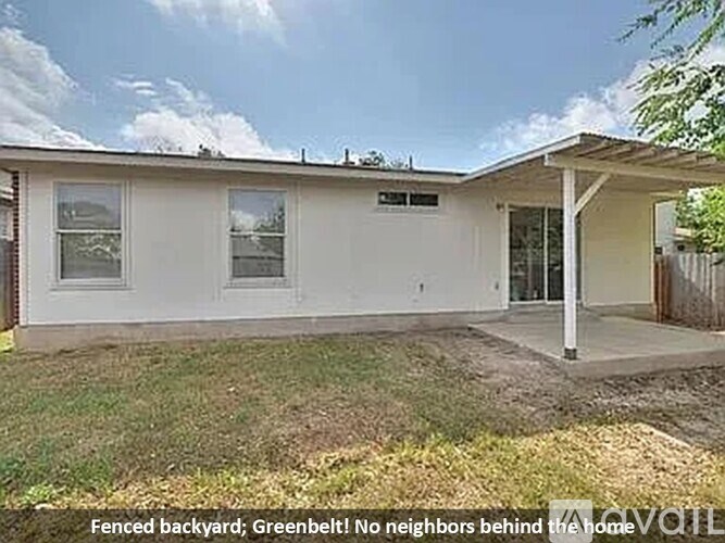 A house with a fenced backyard and greenbelt behind it.