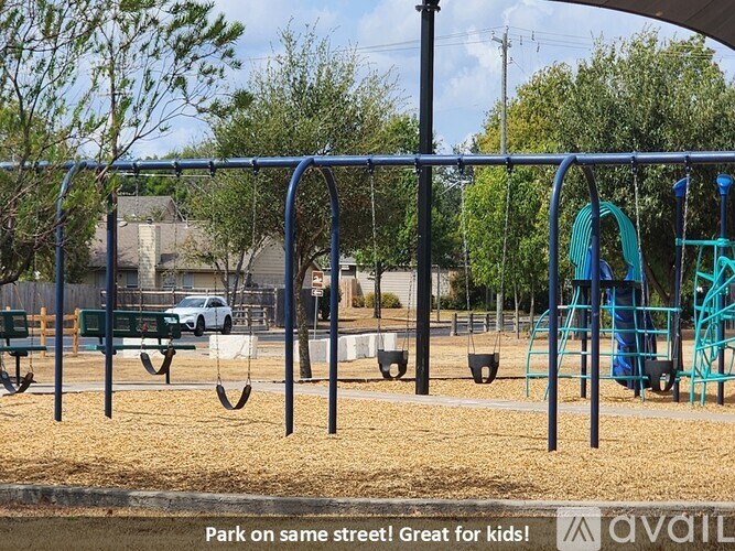 A playground with swings and a slide is located in a park.