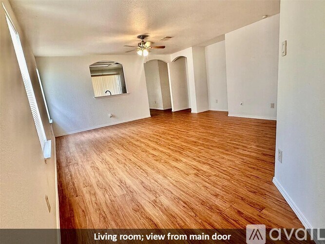 A living room with wooden floors and a ceiling fan.