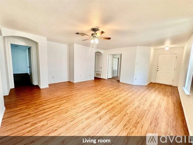 A living room with wood flooring and a ceiling fan.