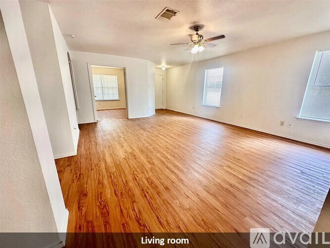 A living room with wooden flooring and a ceiling fan.