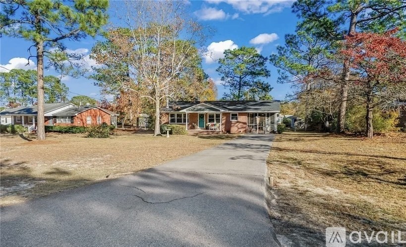 A house with a driveway in front of it surrounded by trees.