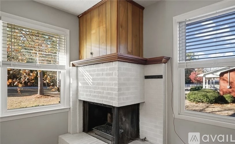 A room with a fireplace and a window showing a house.