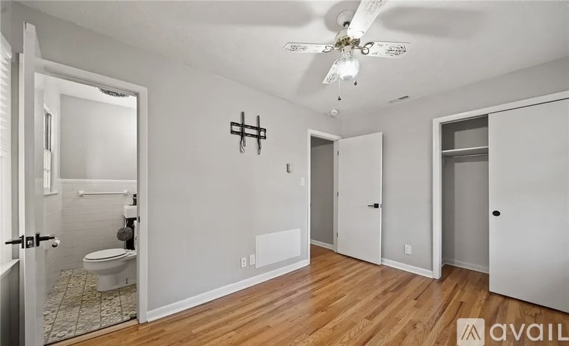 A room with a toilet, a ceiling fan, and a wall hanging.