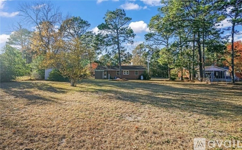 A grassy field with trees and houses in the background.