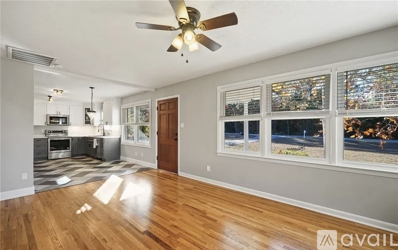 A spacious living room with a ceiling fan and hardwood floors.