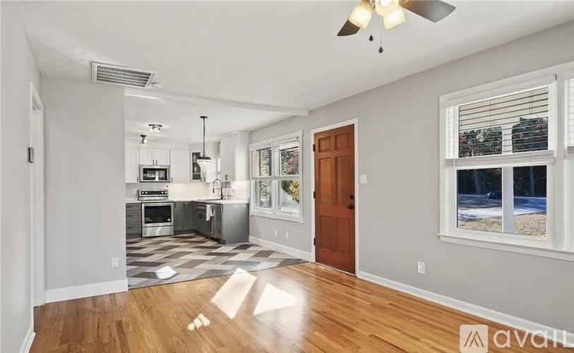 A well-lit, spacious kitchen and living room with hardwood floors and a ceiling fan.