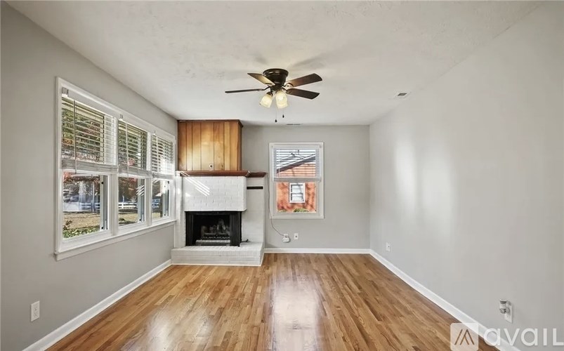 A spacious living room with a fireplace and a ceiling fan.