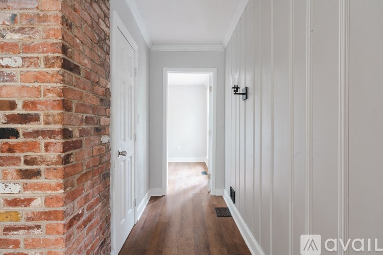 A hallway with a brick wall on the left and white walls on the right.