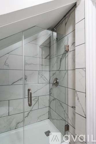 A white bathroom with a marble tile shower.