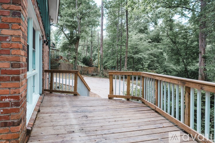 A wooden deck with a railing and a brick building with a blue door.
