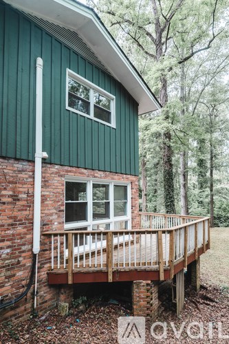 A green house with a white window and a wooden deck.