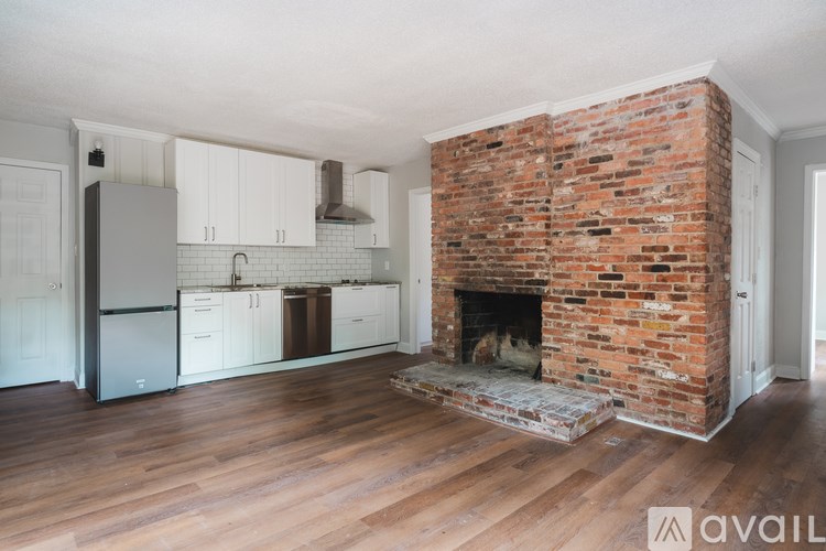 A kitchen with a brick fireplace and wooden floors.