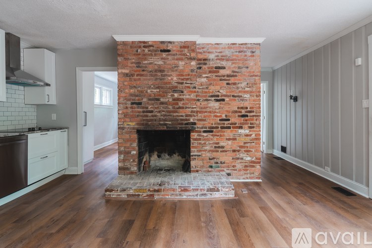 A brick fireplace in a room with wooden floors and white walls.