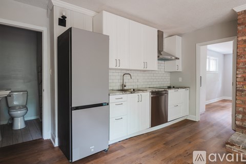 A kitchen with white cabinets and a black fridge.
