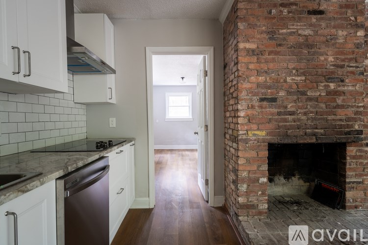 A kitchen with white cabinets and a brick fireplace.
