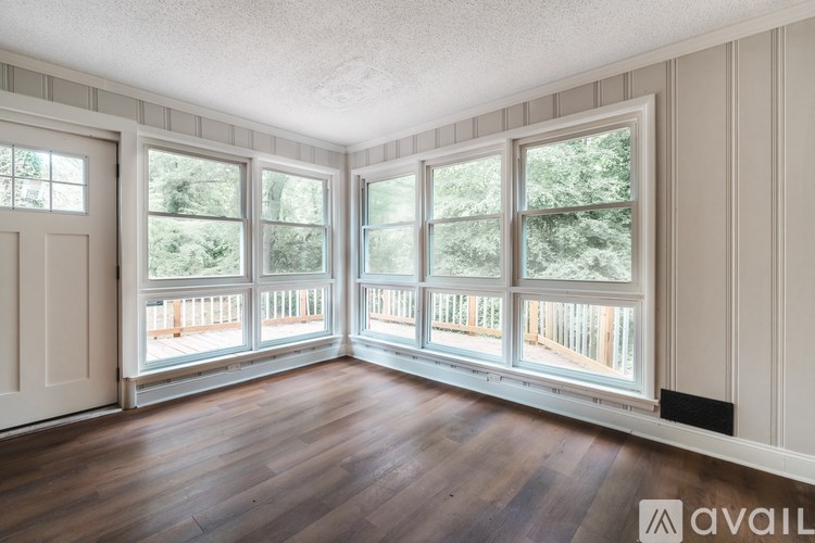 A room with wooden floors and a large window overlooking a deck.