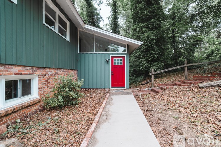 A green house with a red door and a white window.