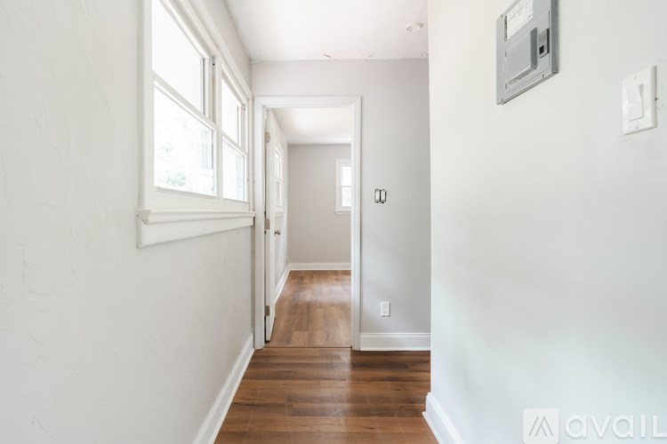 A hallway with a wooden floor and white walls.