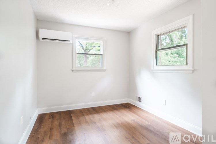 A room with wooden floors and two windows.