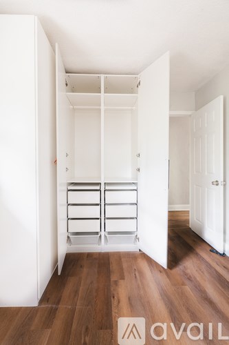 A white closet with shelves and drawers is open to a hallway.