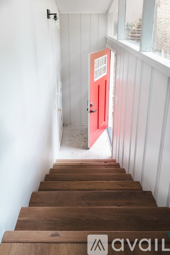 A wooden staircase leading to a red door.