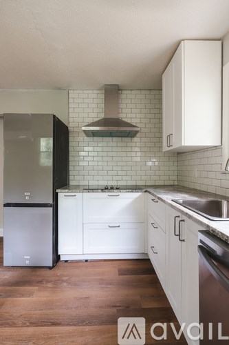 A kitchen with white cabinets and a black fridge.