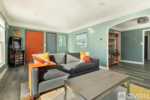 A living room with a grey couch and a glass coffee table.