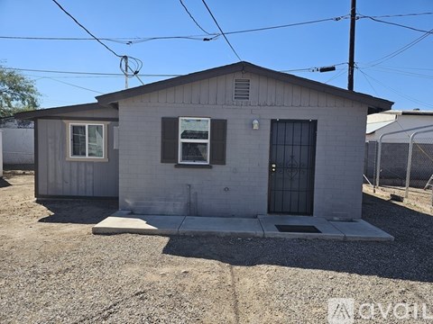 A small grey house with a black door and a window.