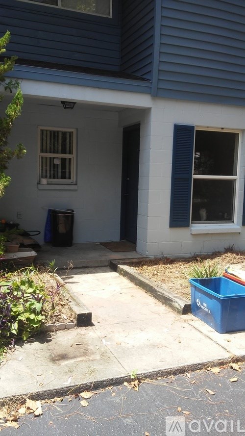 A blue container is on the ground outside a house.