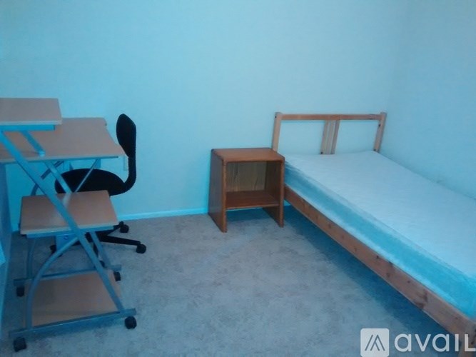 A blue room with a bed, desk, and chair.