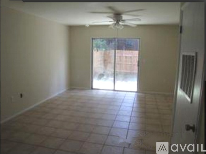 A room with a ceiling fan and sliding glass doors.