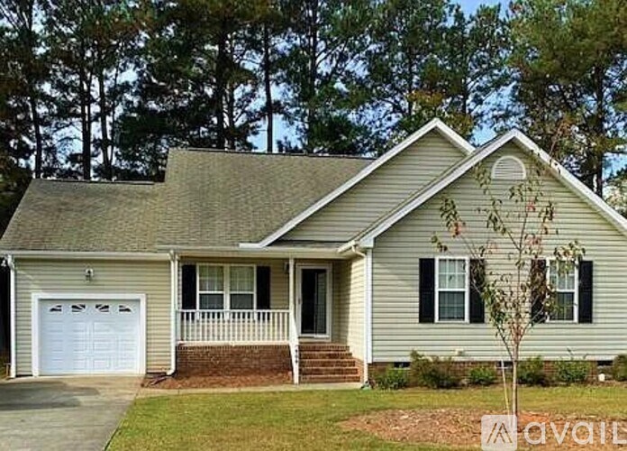 A house with a garage and a tree in front of it.