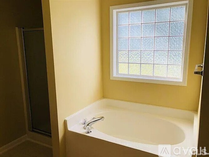 A white bathtub with a window above it in a bathroom.