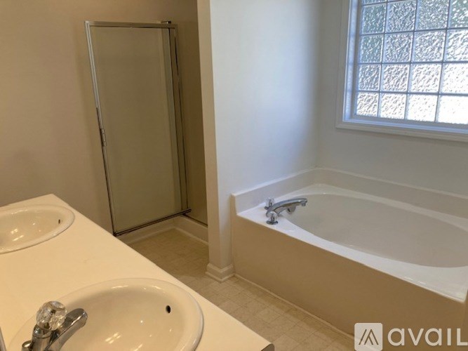 A bathroom with a white tub, sink, and a glass shower door.