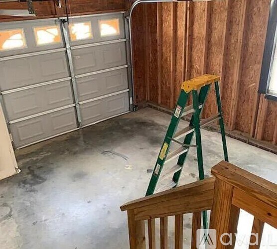 A room with a garage door and a ladder.