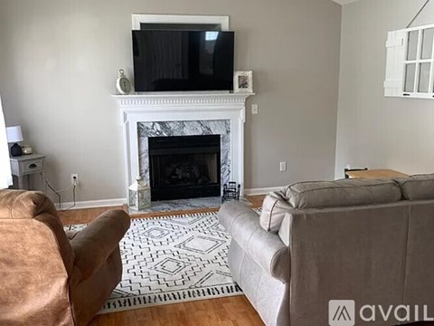 A living room with a fireplace and a television on the wall.