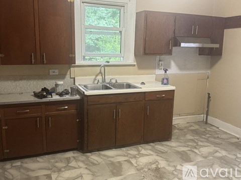 A kitchen with brown cabinets and a marble floor.