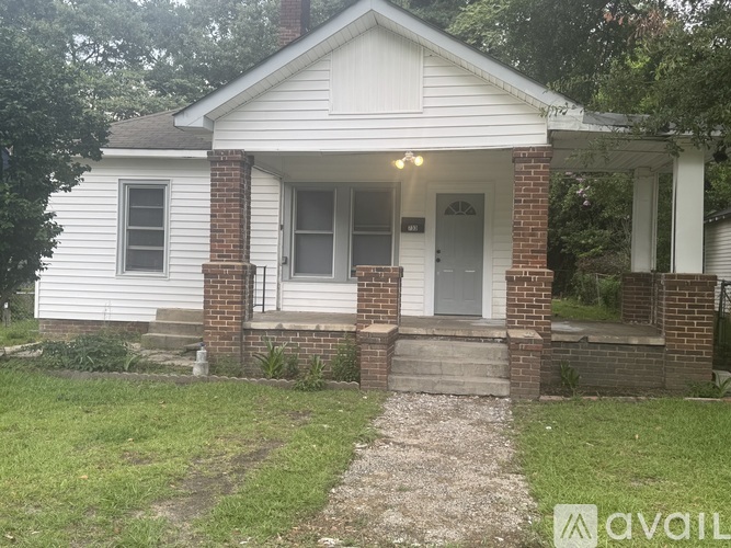 A small white house with a brick pillar and a porch.