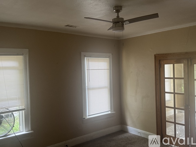 A room with a ceiling fan and two windows.