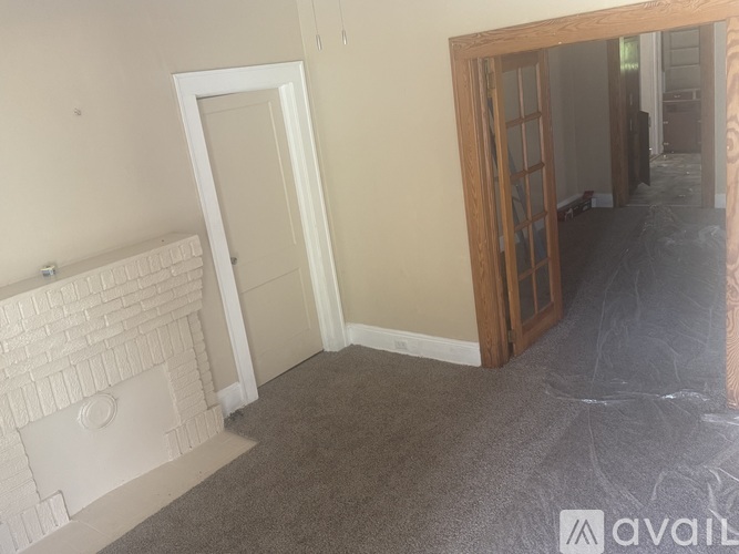 A room with a white door and a fireplace with a white mantle.