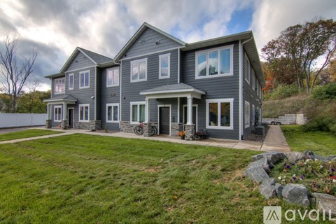 A large house with a grey exterior and a front yard with a stone pathway.