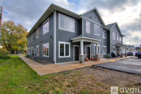 A grey house with a white door and windows is for sale.