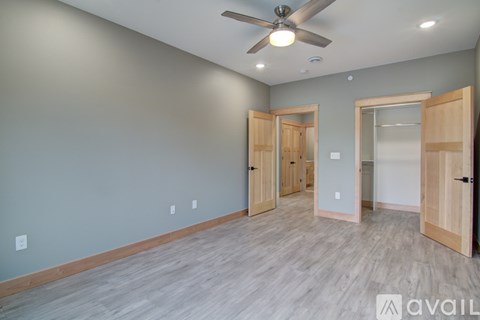 A room with a ceiling fan and wooden flooring.