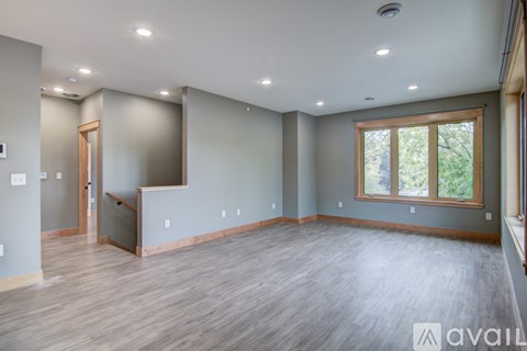 A spacious room with wooden flooring and a large window.