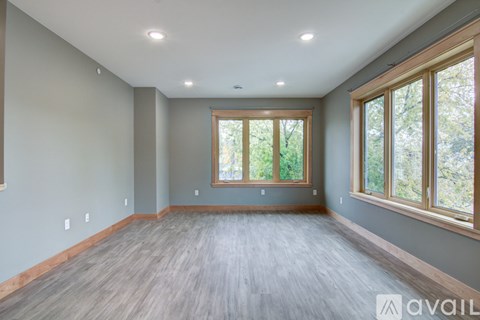 A spacious room with wooden floors and large windows.