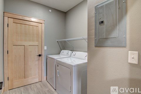 A laundry room with a washer and dryer and a wooden door.